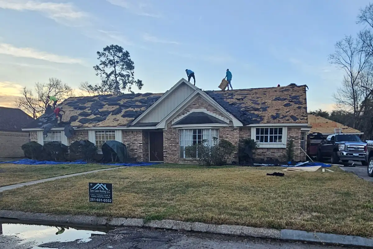 Roofers removing shingles from a roof with exposed decking.