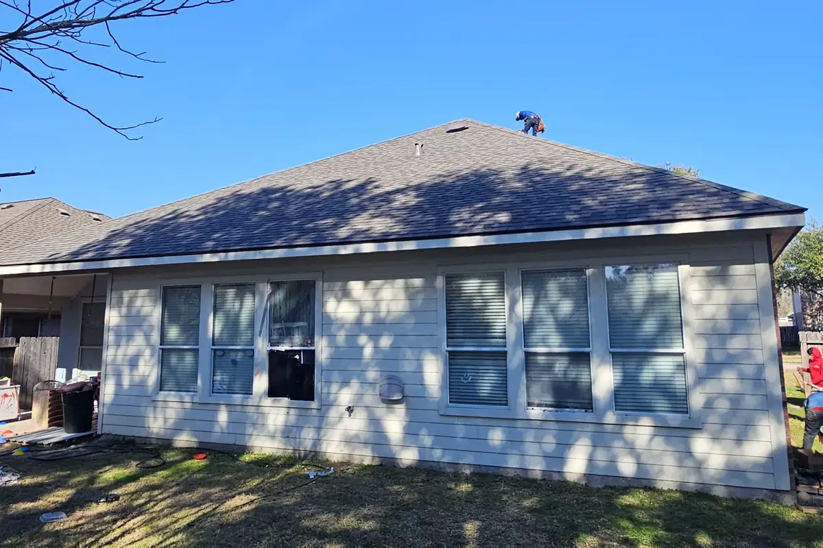 Gray shingle hip roof above a home with white siding.