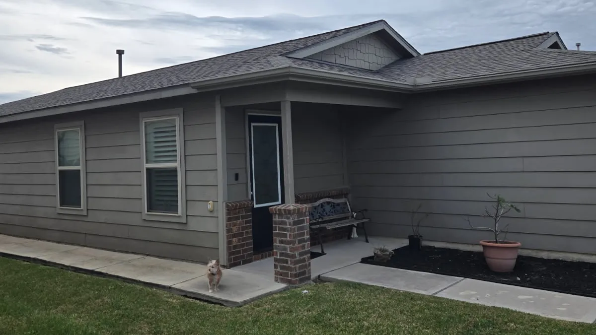 Gray shingle roof and front gable above a home with gray siding.