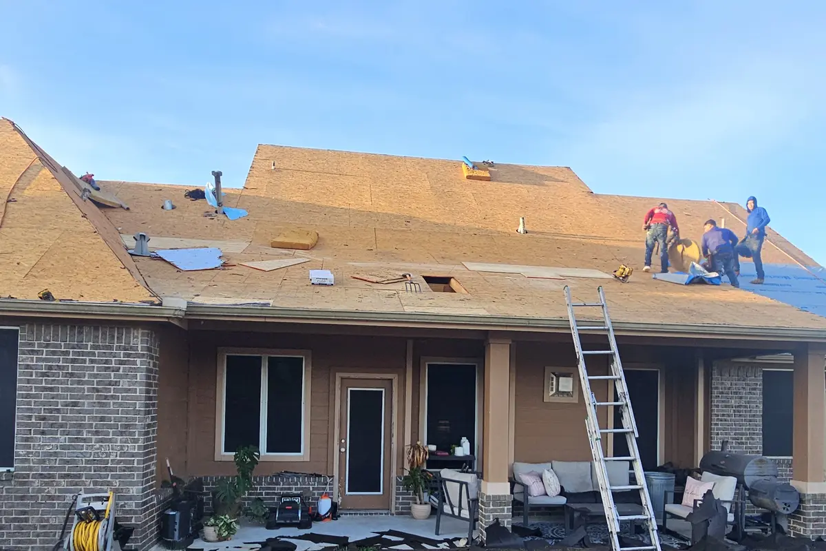 Roofers working on exposed decking above a covered patio.