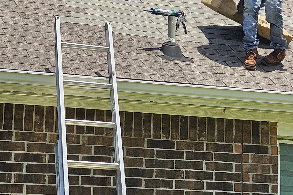 Roof vent flashing above a white gutter beside brickwork.